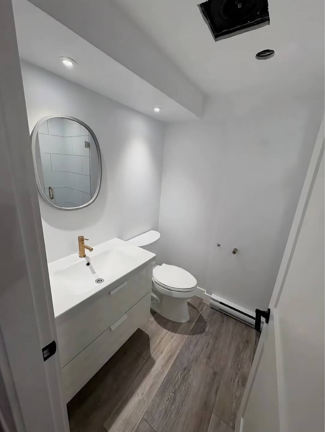 Freshly cleaned modern powder room with white vanity and mirror